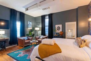 Ein Hotelzimmer mit einem großen Bett, zwei Sesseln, einem Couchtisch, einem Schreibtisch und einem großen Fenster.