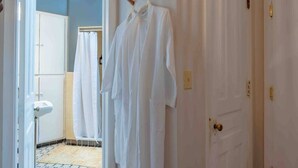 Un couloir avec une porte blanche, un porte-serviettes blanc avec des serviettes, un lavabo blanc et un mur bleu.
