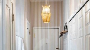 Un couloir avec des portes blanches, un luminaire suspendu et un tapis à motifs.