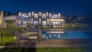 Et moderne hus med to etager, en swimmingpool, udendørs siddepladser og en veloplyst patio.
