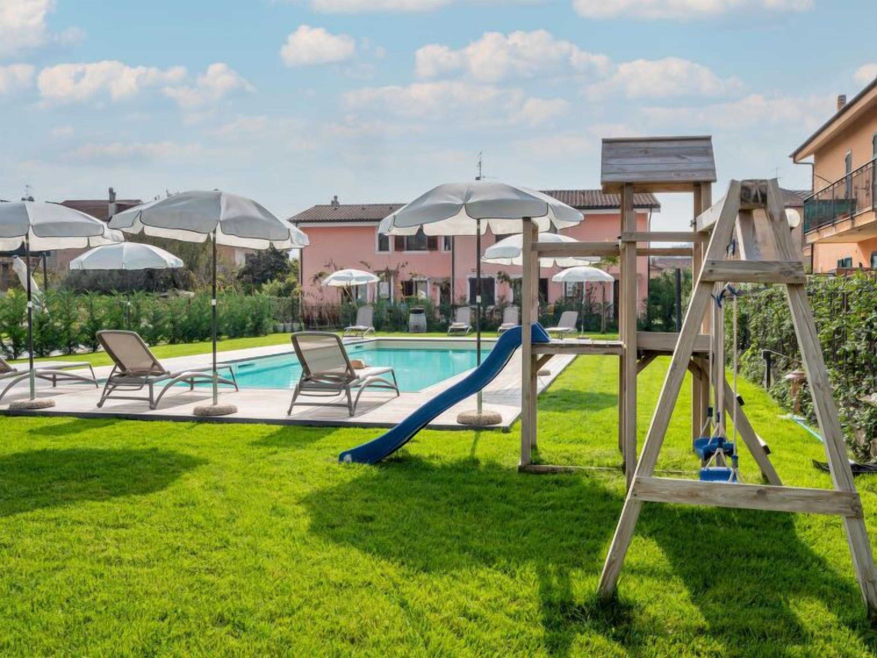 Un espace piscine équipé de chaises longues, de parasols et d’un toboggan.