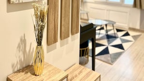 Una sala de estar moderna con una mesa de centro de madera, un florero con flores secas, un espejo grande y una alfombra con motivos geométricos.