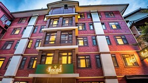 A multi-story building with a prominent 'Muscatel DZEEMKHANG' sign. - Muscatel Dzeemkhang (Gangtok)