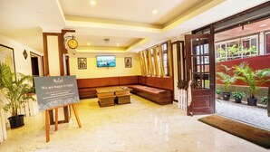 A hotel lobby with a reception desk, seating area, and a view of the outside. - Muscatel Dzeemkhang (Gangtok)