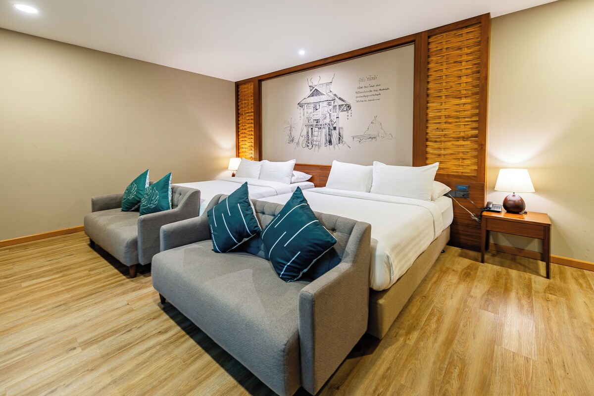 A hotel room with a large bed, two sofas, a small table, and a wall mural.