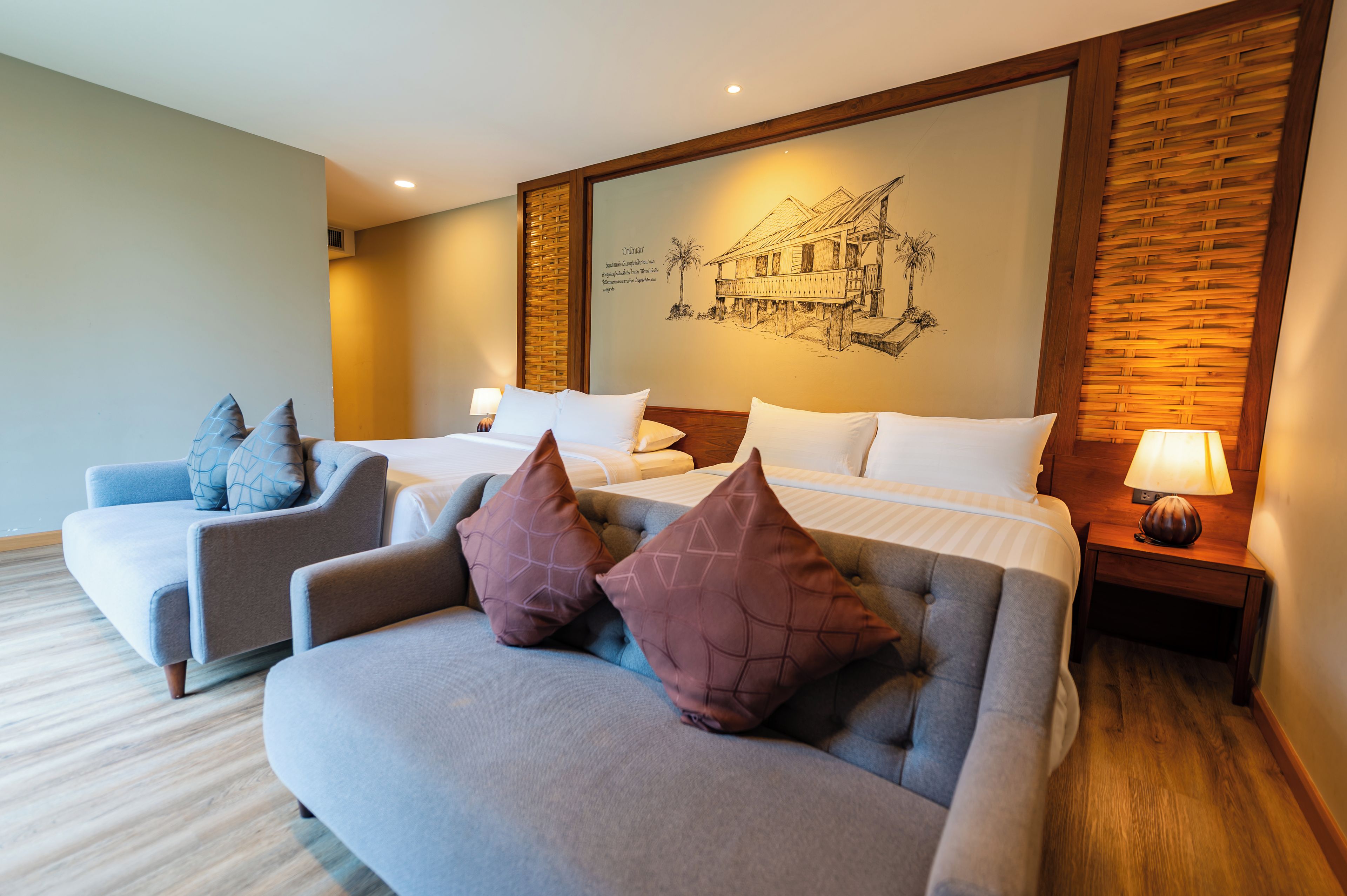 A hotel room with a large bed, two sofas, a wooden accent wall, and a wall-mounted artwork.