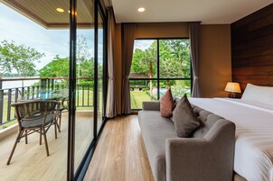 Habitación de hotel con balcón, sofá, cama y mesa con sillas.