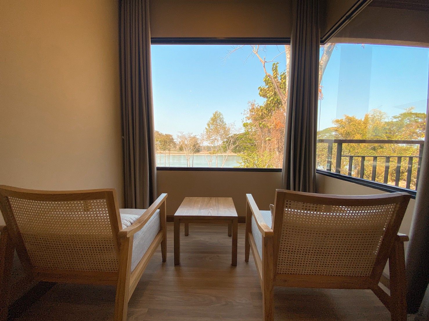A balcony with a table and two chairs, overlooking a body of water and trees.