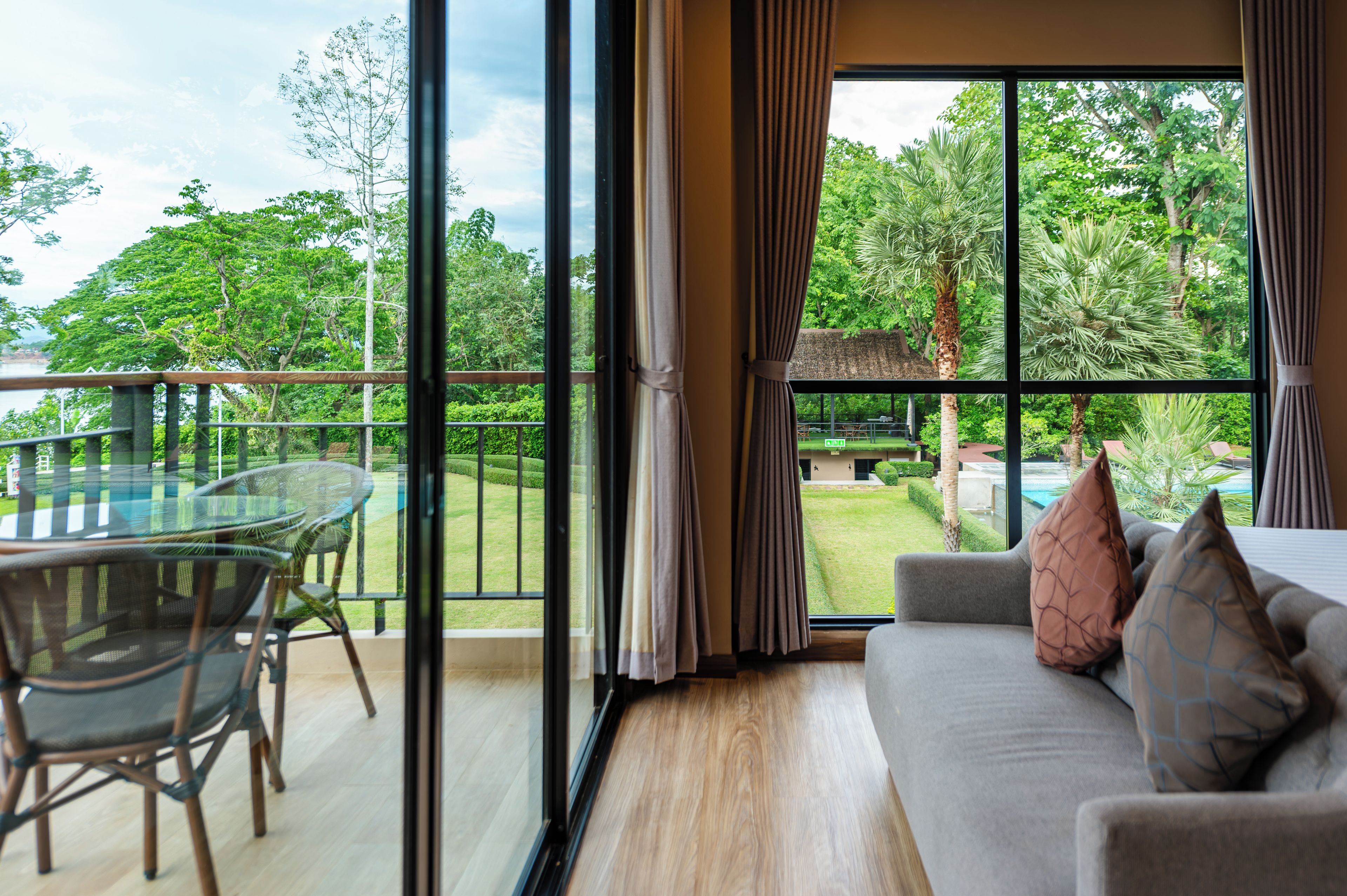 A room with a large window, a sofa, and a glass table with chairs.