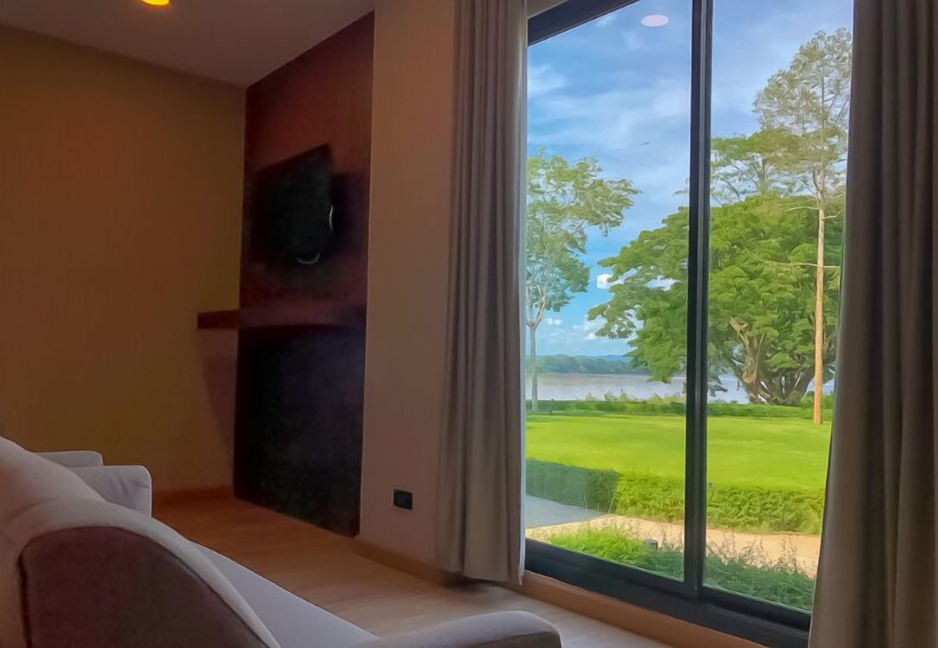 A modern room with a large window offering a view of a green landscape and a body of water.