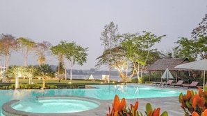 A swimming pool with a circular design, surrounded by lounge chairs and a thatched-roof structure. - RiverTree Resort Chiangkhan  (Chiang Khan)