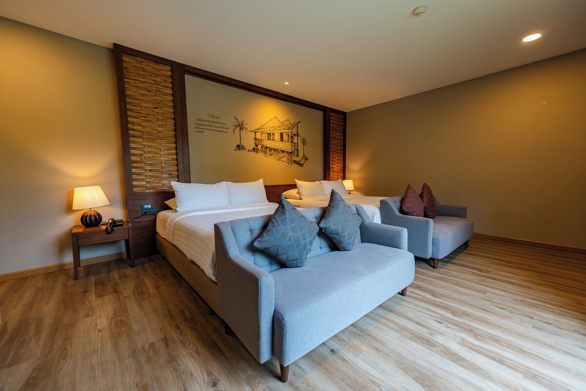 A hotel room with a bed, two armchairs, a nightstand, and a wall with a mural.
