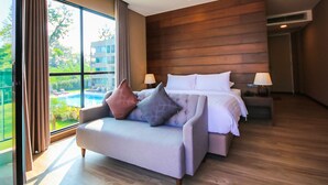 A modern hotel room with a large bed, a sofa, and a view of a swimming pool. - RiverTree Resort Chiangkhan  (Chiang Khan)