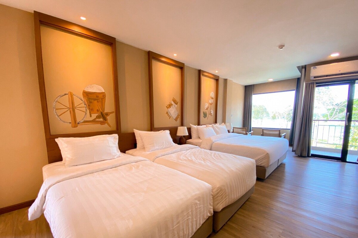 A hotel room with three beds, a large window, and a balcony.