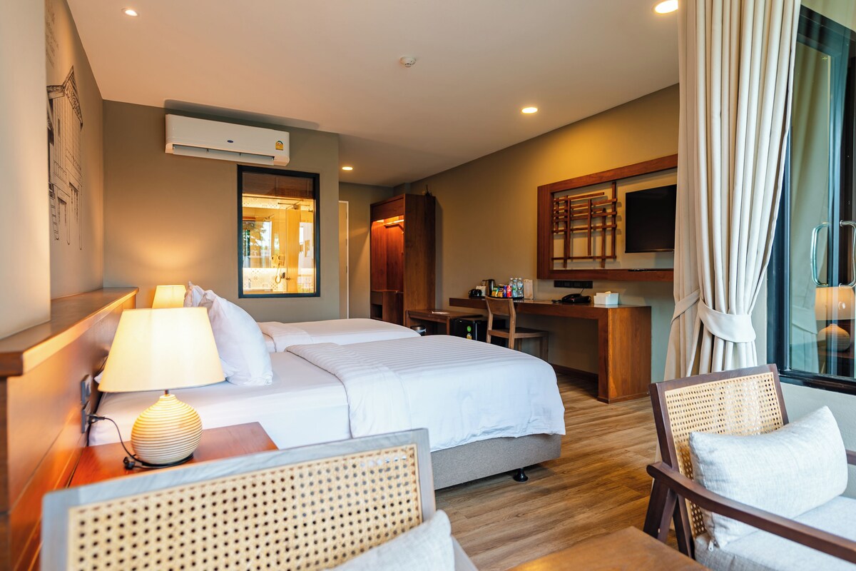 A hotel room with a bed, a desk, a chair, and a television.