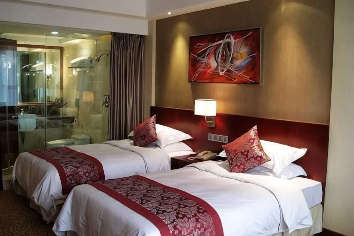 Une chambre d’hôtel avec deux lits, une douche en verre et un tableau au mur.