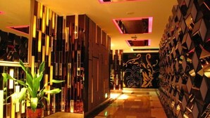 A modern hotel lobby with a geometric patterned wall, a potted plant, and a decorative wall with a floral design. - Xiangcheng International Hotel (Pingxiang)