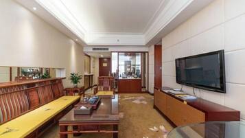 A hotel room with a wooden dining table, a sofa, a TV, and a cabinet.