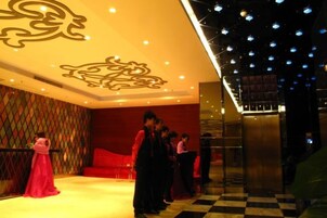Vestíbulo de hotel con suelo a cuadros, una escalera y un diseño decorativo en el techo.