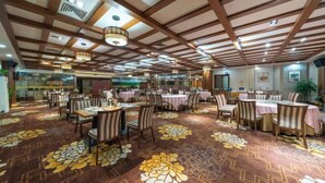 A spacious dining area with multiple tables and chairs, a patterned carpet, and a wooden ceiling structure. - Xiangcheng International Hotel (Pingxiang)