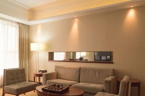 A hotel room with a sofa, armchairs, a coffee table, a lamp, and a flat-screen TV mounted on the wall. - Xiangcheng International Hotel (Pingxiang)