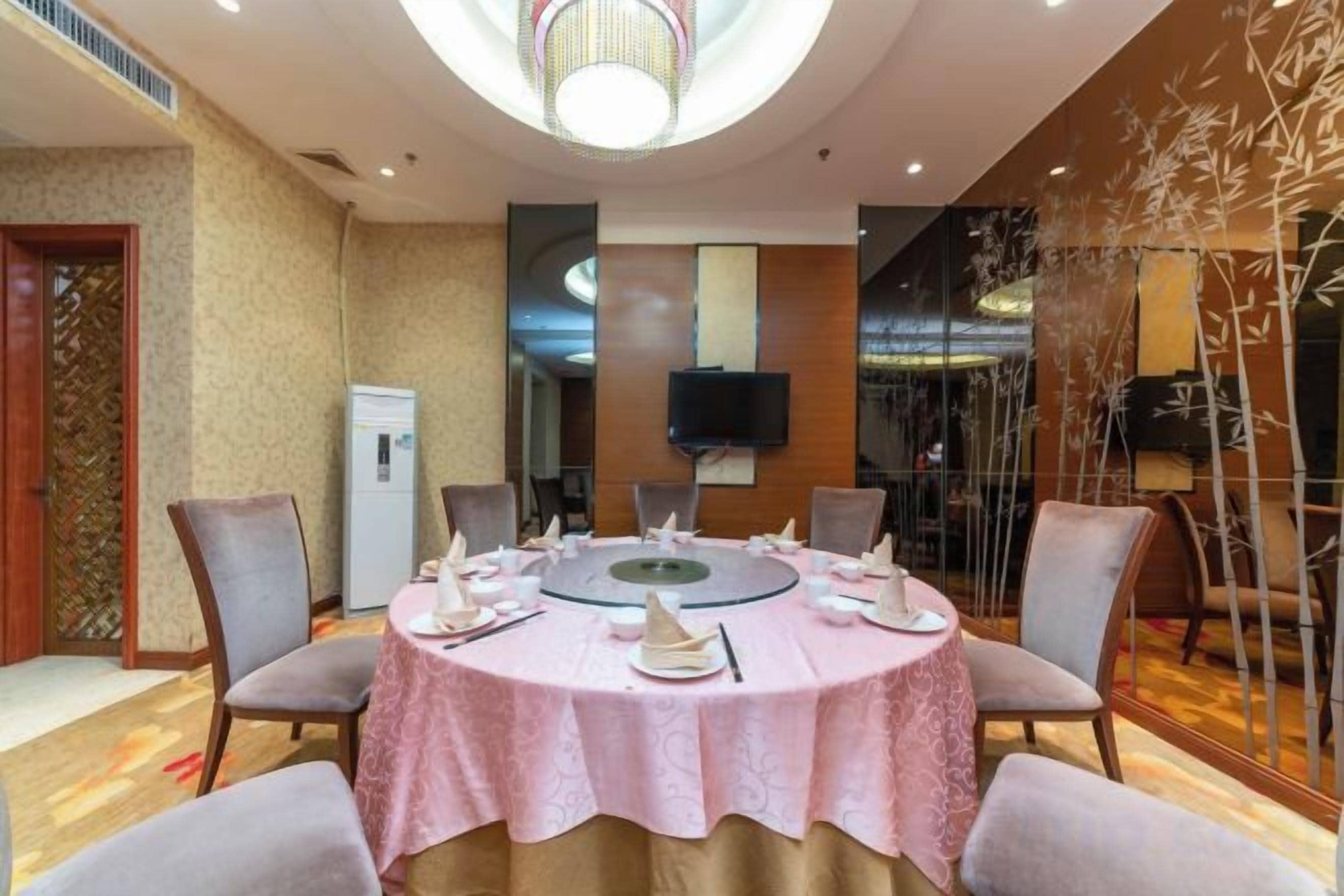 A conference room with a round table, chairs, and a television screen on the wall.