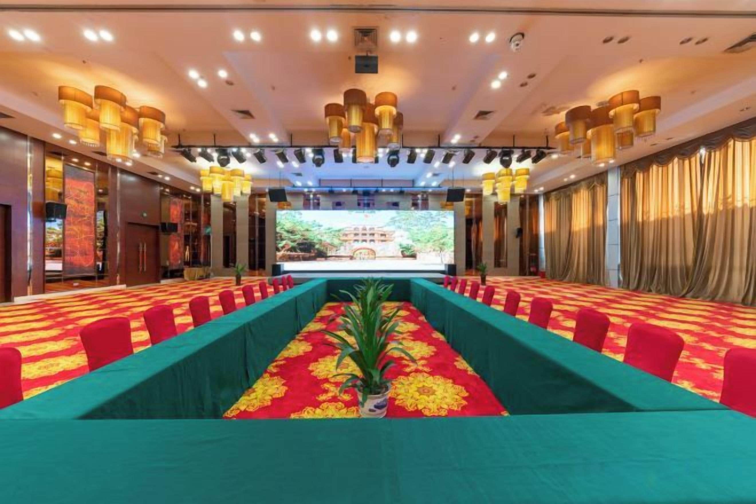 A conference room with a long table, chairs, and a stage with curtains.
