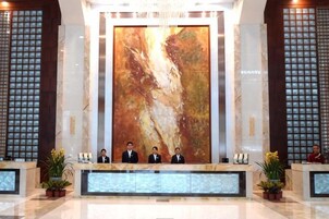Un área de recepción con un cuadro abstracto de gran tamaño, un mostrador de mármol y un diseño simétrico con ventanales altos.