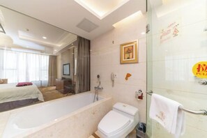 A modern bathroom with a bathtub, toilet, and glass shower enclosure. - Xiangcheng International Hotel (Pingxiang)