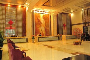Un vestíbulo de hotel con mostrador de recepción, zona de estar y elementos decorativos.