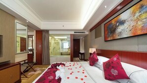 A hotel room with a bed, a large painting, and a view of the bathroom. - Xiangcheng International Hotel (Pingxiang)