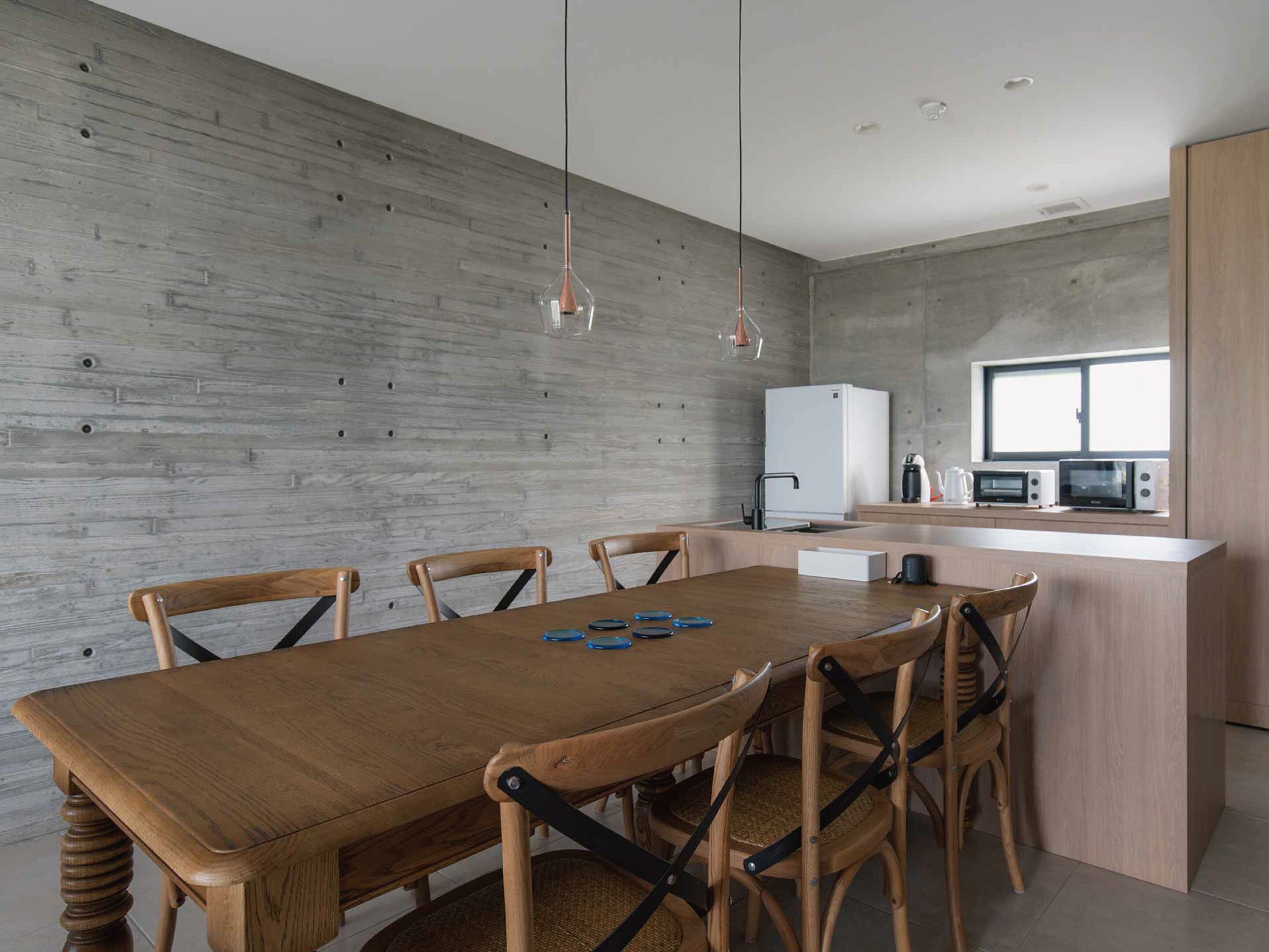 Una cocina moderna con una mesa y sillas de madera, un refrigerador blanco y microondas integrados.