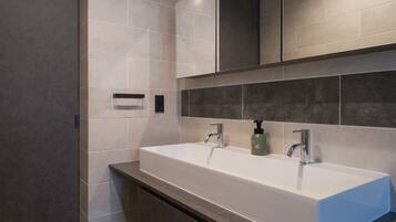 A modern bathroom with a large white sink, dark tiles, and a mirror above.
