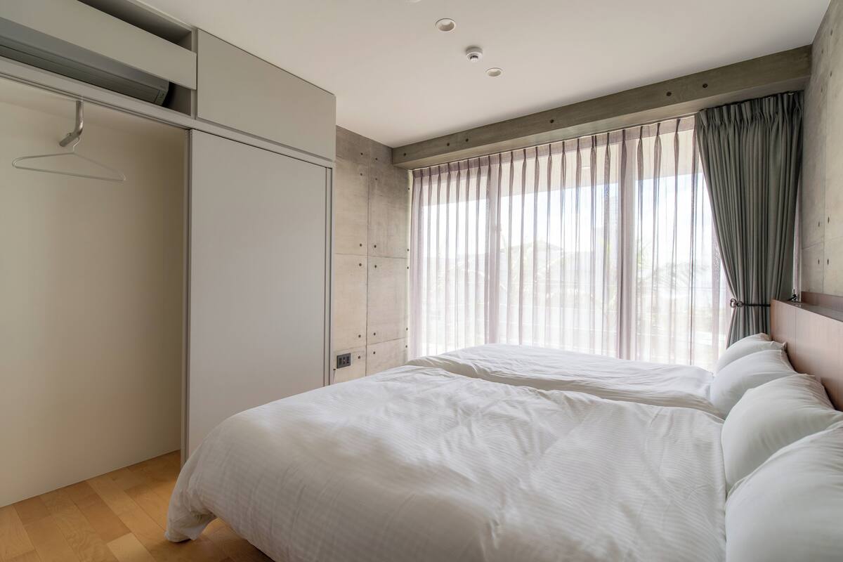A bedroom with a bed, a wardrobe, and a window with curtains.