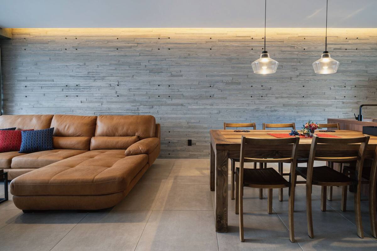 A modern living room with a brown leather sofa, wooden dining table, and chairs.