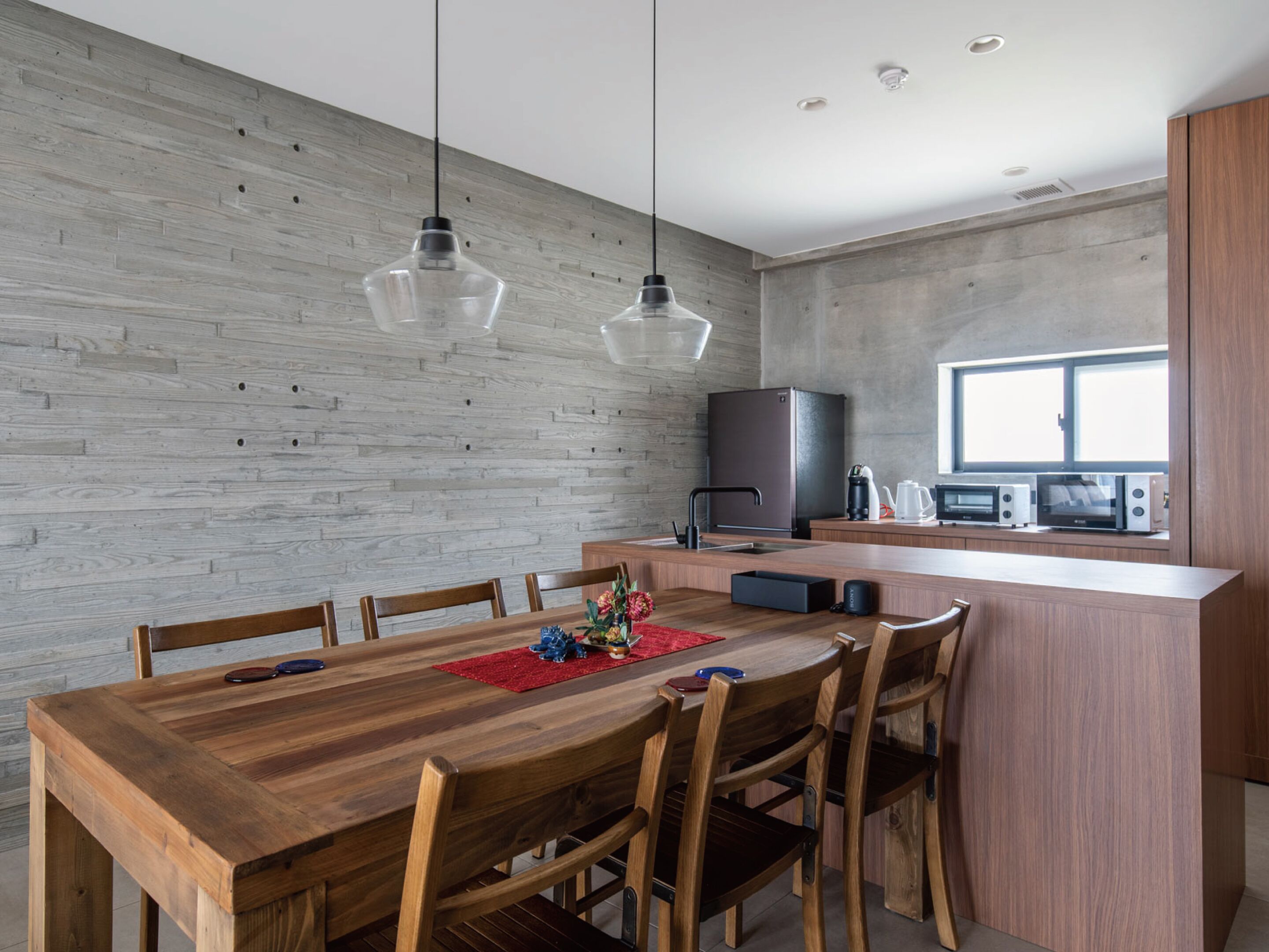 Una cocina moderna con una isla de madera, electrodomésticos integrados y una zona de comedor con mesa y sillas de madera.