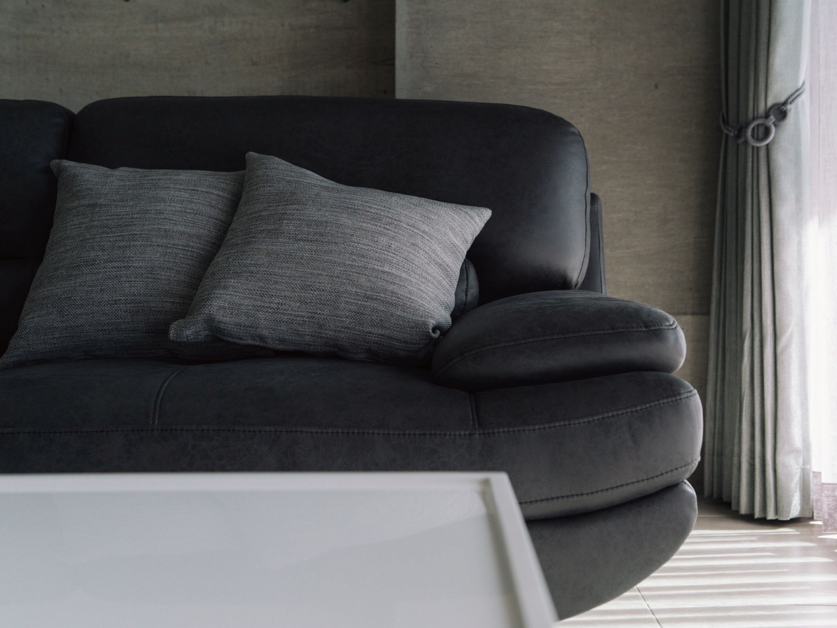 A modern living room with a black sofa and two grey pillows.