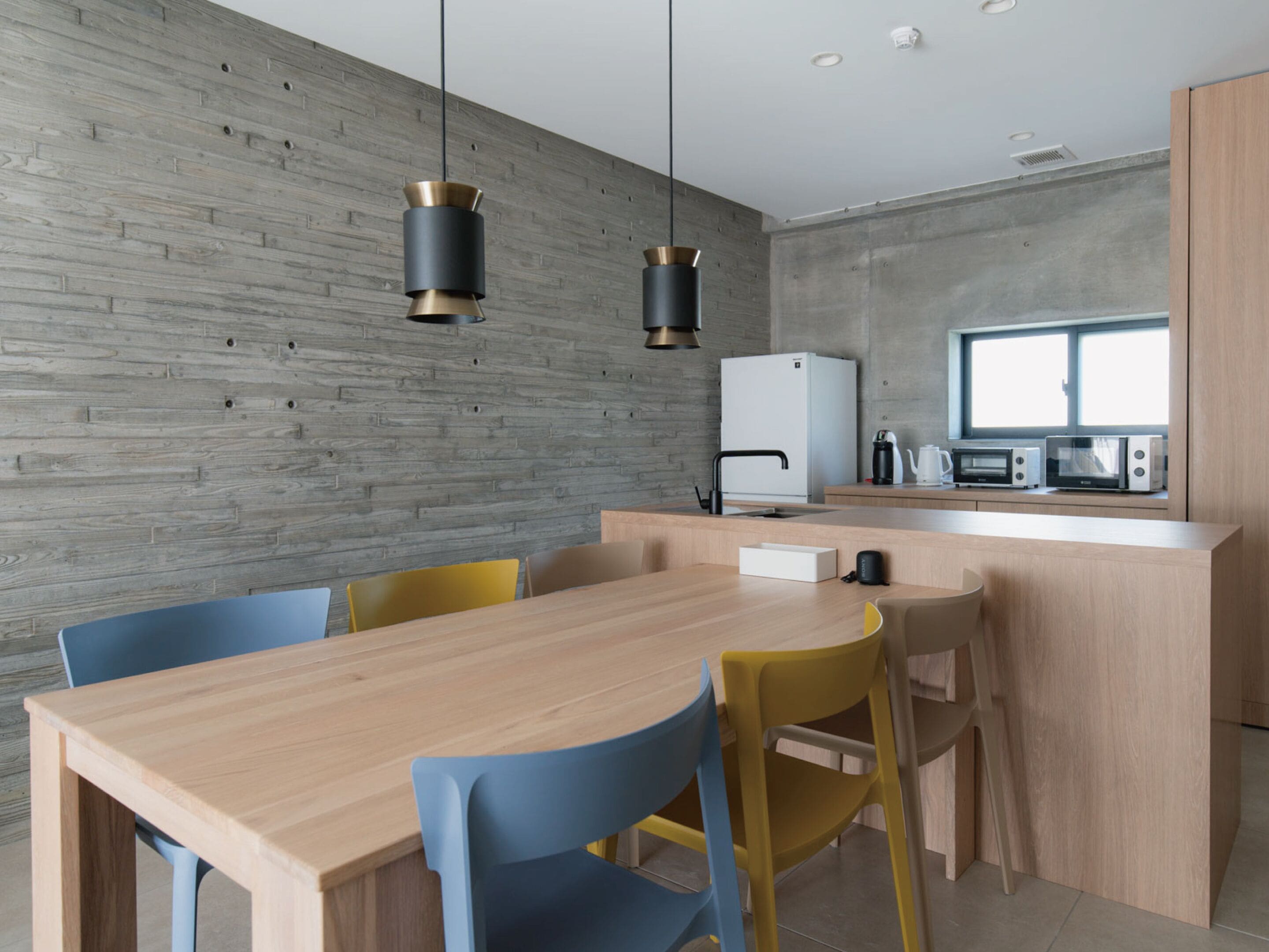 Una cocina moderna con una pared de madera, una isla central y un comedor con sillas.
