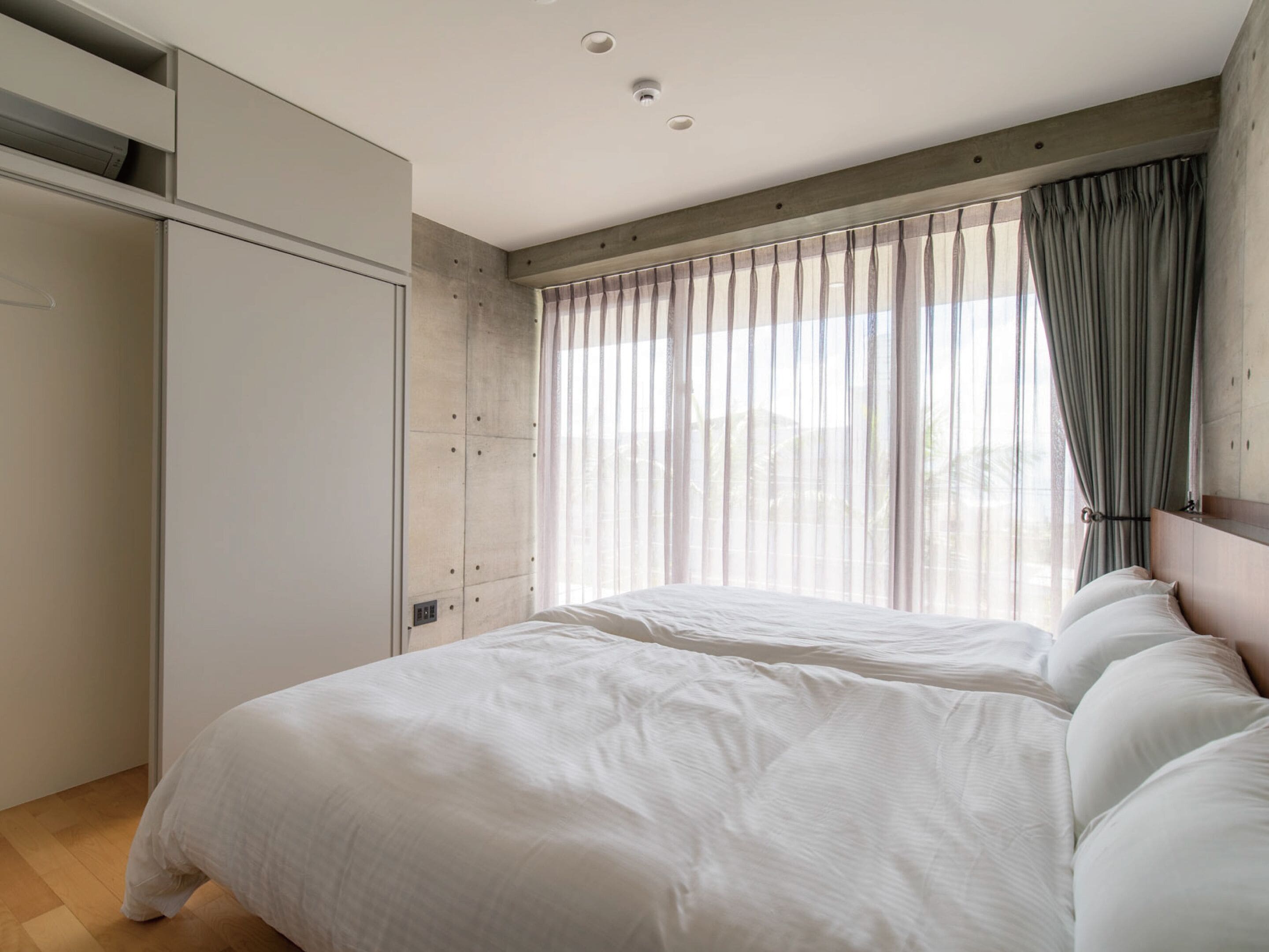A bedroom with a bed, a wardrobe, and a window with curtains.