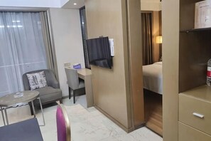 Ett hotellrum med en säng, en tv, ett skrivbord, en stol och ett litet bord.