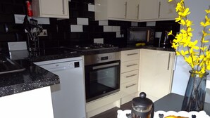 Cocina equipada con lavavajillas, horno, microondas y cafetera. Hay dos cruasanes en un plato.