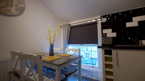Un espacio habitable compacto con comedor, kitchenette y vistas a la ciudad a través de una ventana.