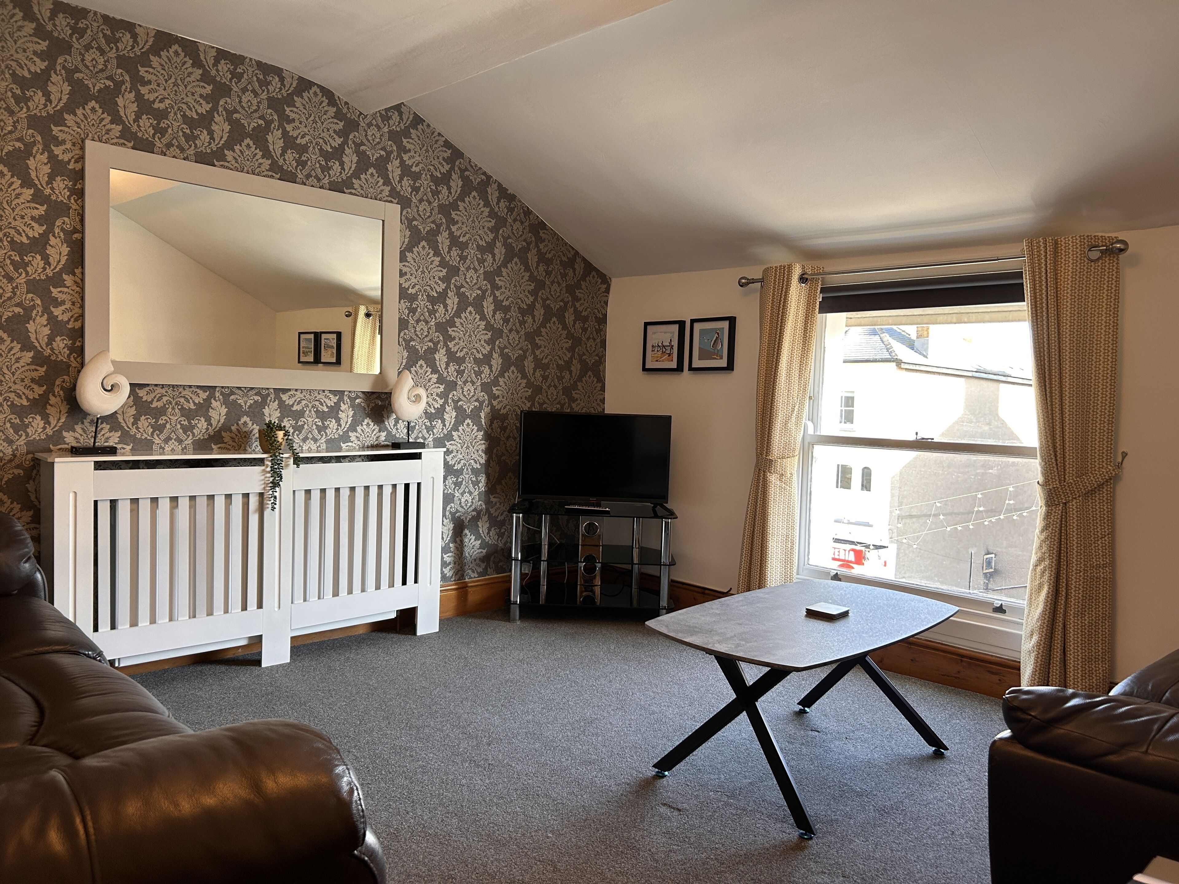 A living room with a white radiator, a television, a small table, and a sofa.