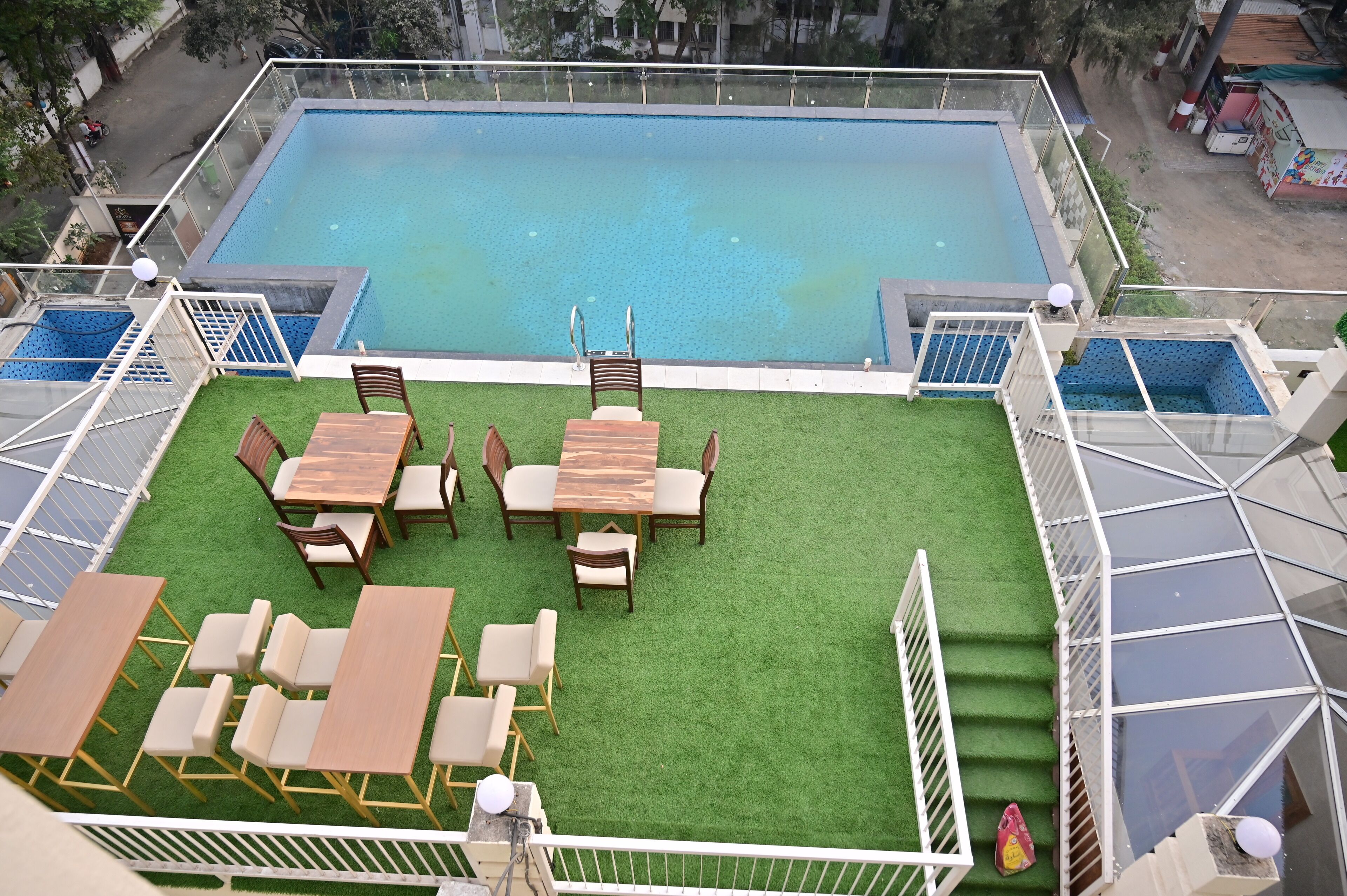 A rooftop pool with a wooden deck and seating area.