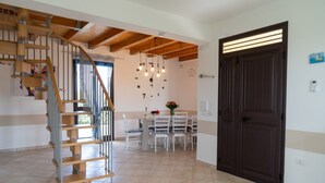 Un vaste espace de vie agrémenté d’un escalier en bois, d’une table à manger avec des chaises et d’une porte en bois foncé.