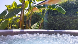 Un bain à remous où l’eau bouillonne, entouré de luxuriants bananiers et d’un feuillage dense.