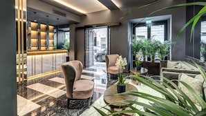 A modern lobby with a reception desk, seating area, and large windows. - CC Palace Hotel Roma (Rome)