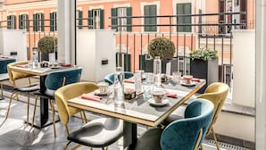 A rooftop terrace with tables and chairs, a view of buildings, and a metal railing. - CC Palace Hotel Roma (Rome)