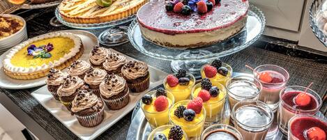 A variety of desserts on display, including cakes, cupcakes, and fruit-topped drinks.