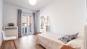 Um quarto com cama, escrivaninha, cadeira, guarda-roupa e janela com cortinas.